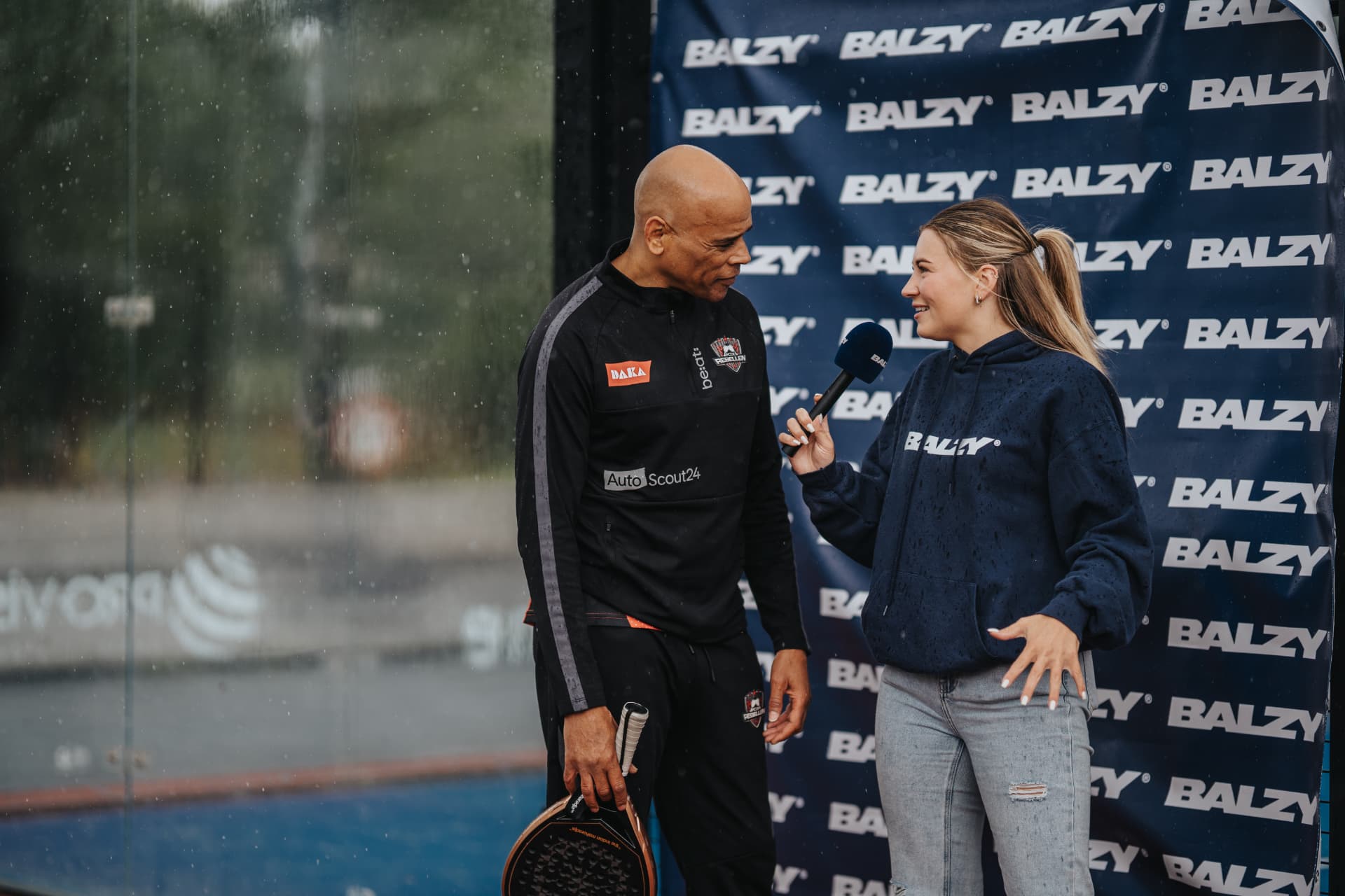Rebel wordt geinterviewd voor de sponsorwand langs de baan