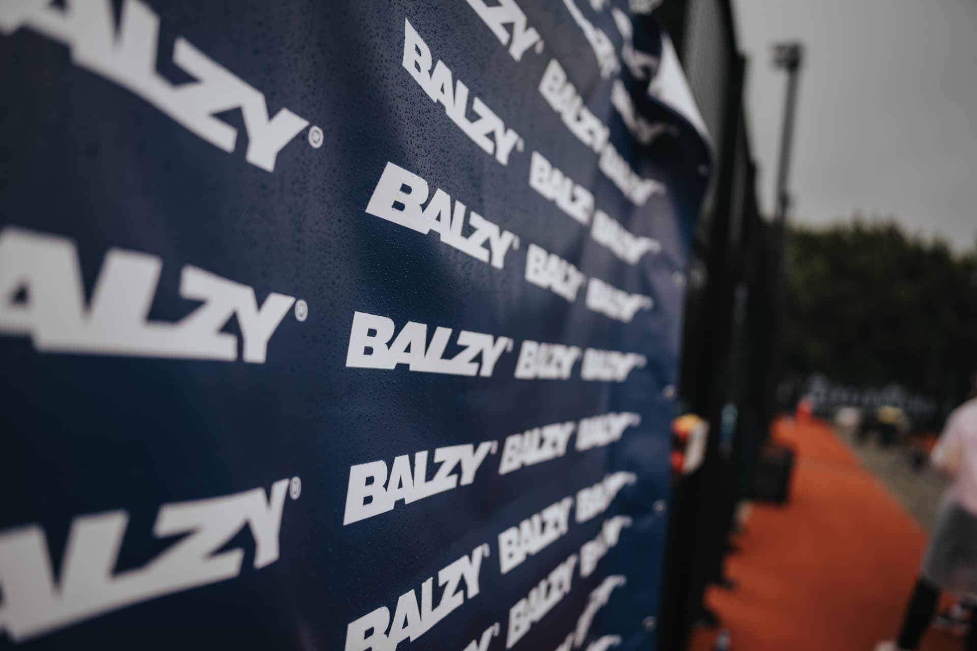 Sponsordoek met logo's langs de padelbaan