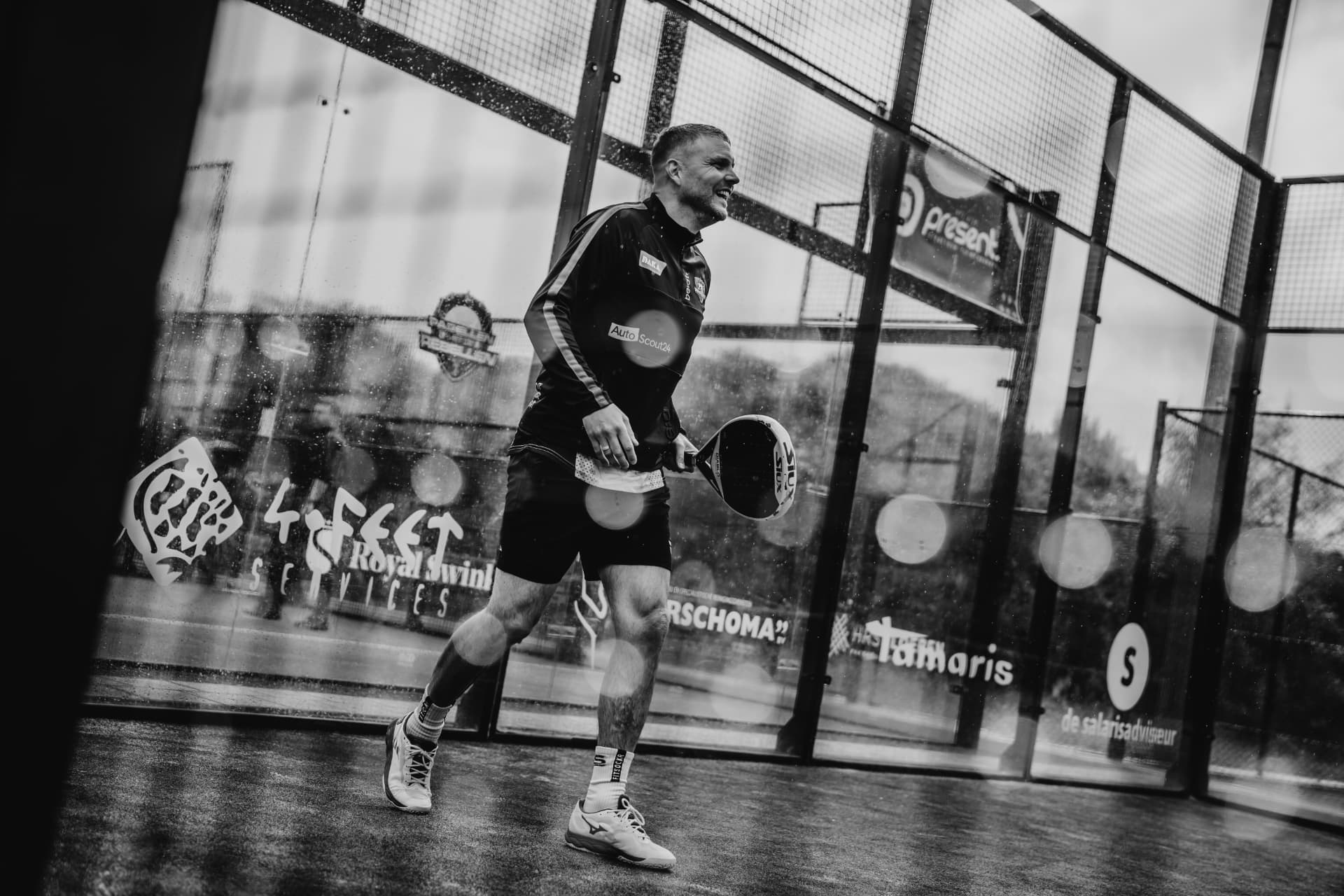 Lachende speler loopt over de baan met zijn racket in de hand