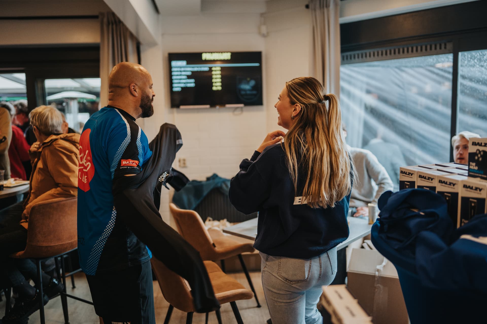 Deelnemer krijgt een shirt van een sponsor uitgereikt in het clubhuis